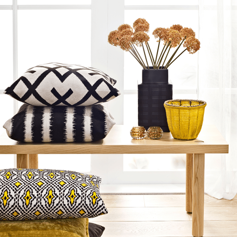 a table with pillows and a vase with flowers on it